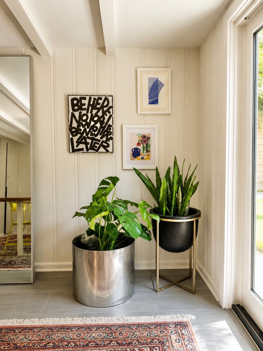 Dining room corner with gallery wall and planters beside the glass doors