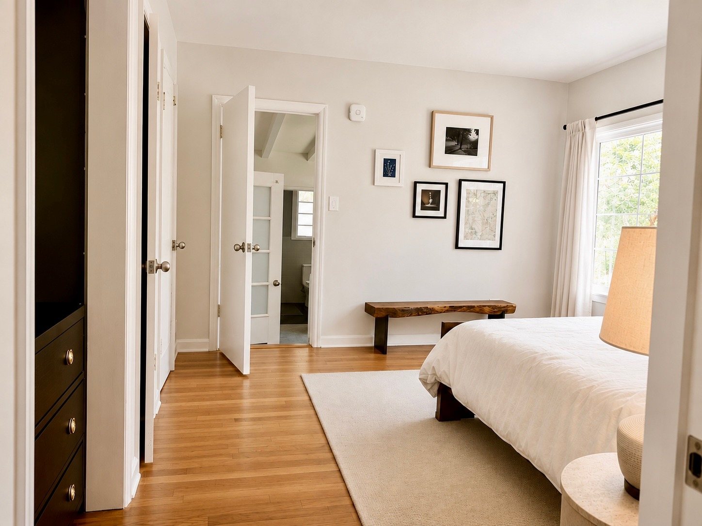 Bedroom with wood bench, gallery wall, and adjoining bath